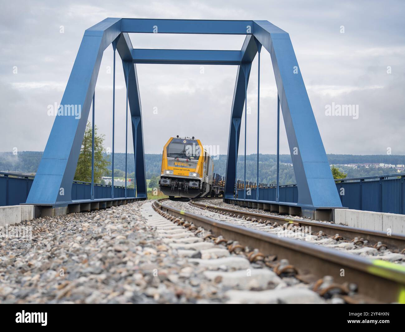 Train jaune sur pont bleu au-dessus des rails par temps nuageux, construction de voies, livraison ferroviaire pour Hermann Hessebahn, Calw, Forêt Noire, Allemagne, Europe Banque D'Images