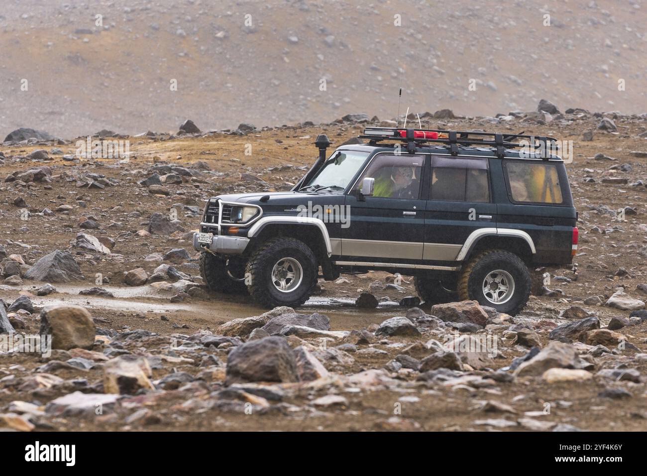 Vus japonais Toyota Land Cruiser Prado conduite sur route de montagne rocheuse sur fond volcanique paysage. Vacances actives, voyage tout-terrain dans la pluie Banque D'Images
