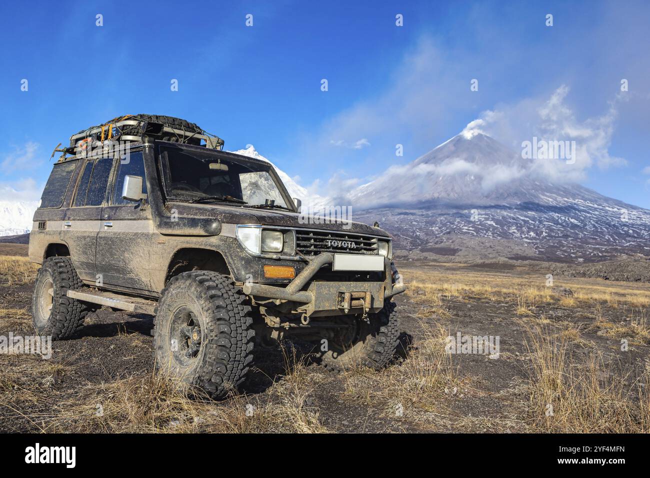 Véhicule utilitaire sport soulevé Toyota Land Cruiser Prado en arrière-plan éruption active volcan Klyuchevskoy. Transmission modifiée par la voiture pour le déplacement, par exemple Banque D'Images