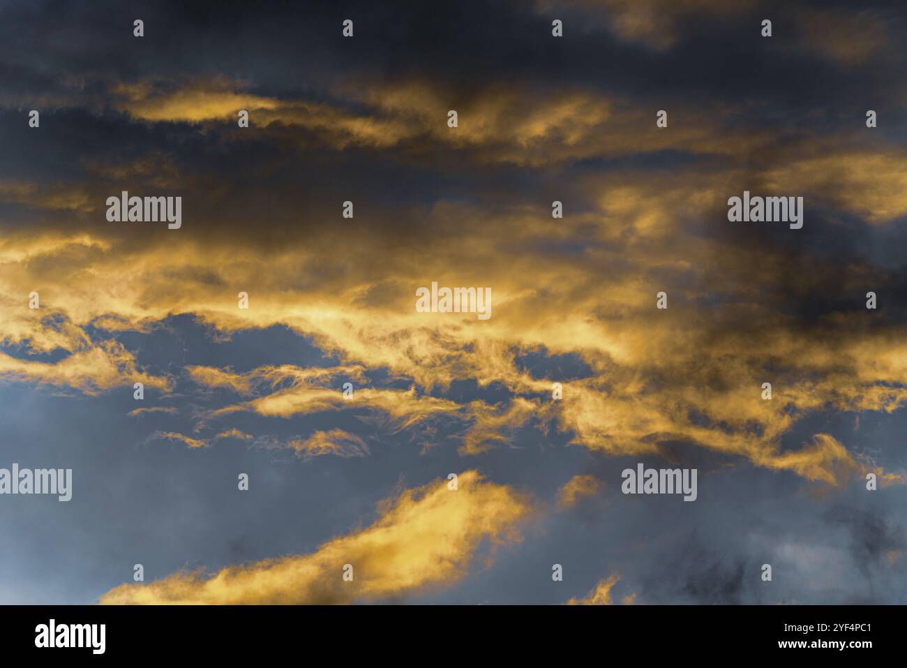 Belle vue météorologie naturelle fond abstrait. Nuages moelleux illuminés par des rayons disparaissant au coucher du soleil et des nuages d'orage sombres flottant à travers Banque D'Images