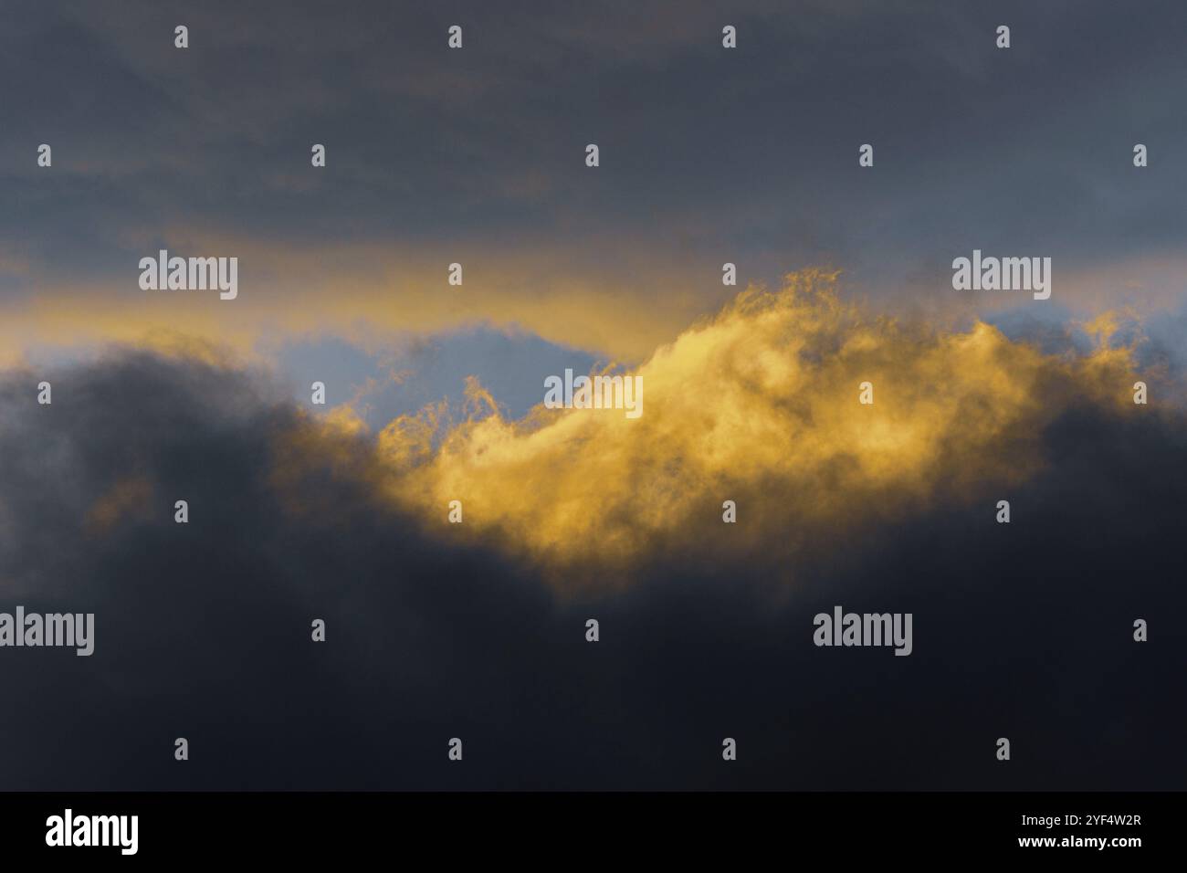 Nuages moelleux illuminés par la disparition des rayons au coucher du soleil et les orages sombres flottant à travers le ciel bleu ensoleillé pour changer le temps de saison. Vue magnifique Banque D'Images