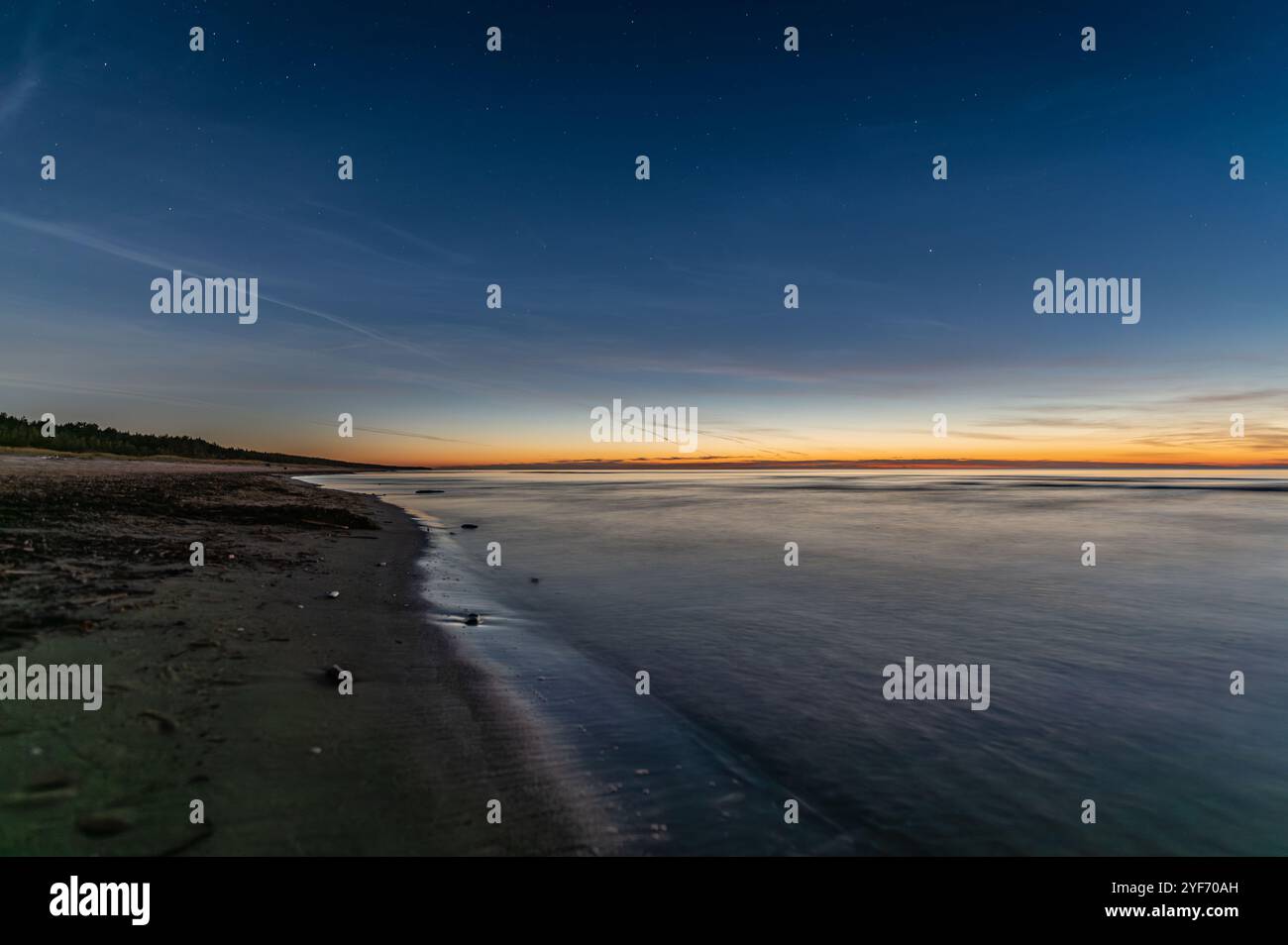 Plage de la mer Baltique en Lettonie à l'automne après le coucher du soleil, les étoiles et la comète C 2023 A3 Tsuchinshan–ATLAS loin dans le ciel. Banque D'Images