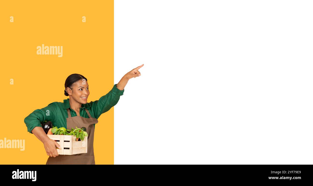 Femme souriante avec un panier de légumes points avec enthousiasme à l'intérieur Banque D'Images
