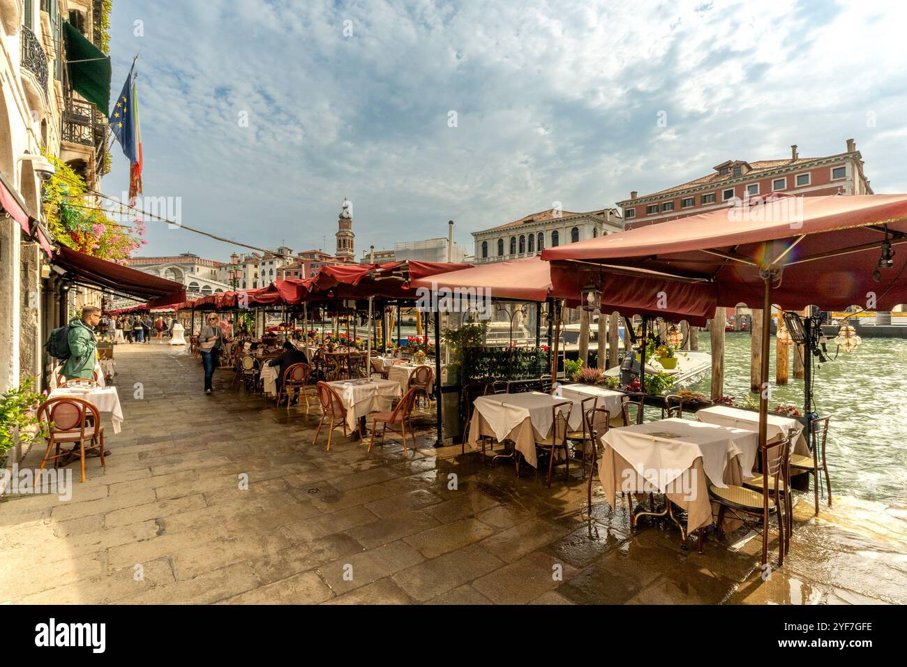 Venise, Vento – IT – Oct 14, 2024 Un charmant café au bord du canal à Venise avec des auvents rouges, des nappes blanches et une vue panoramique sur les bâtiments historiques Banque D'Images