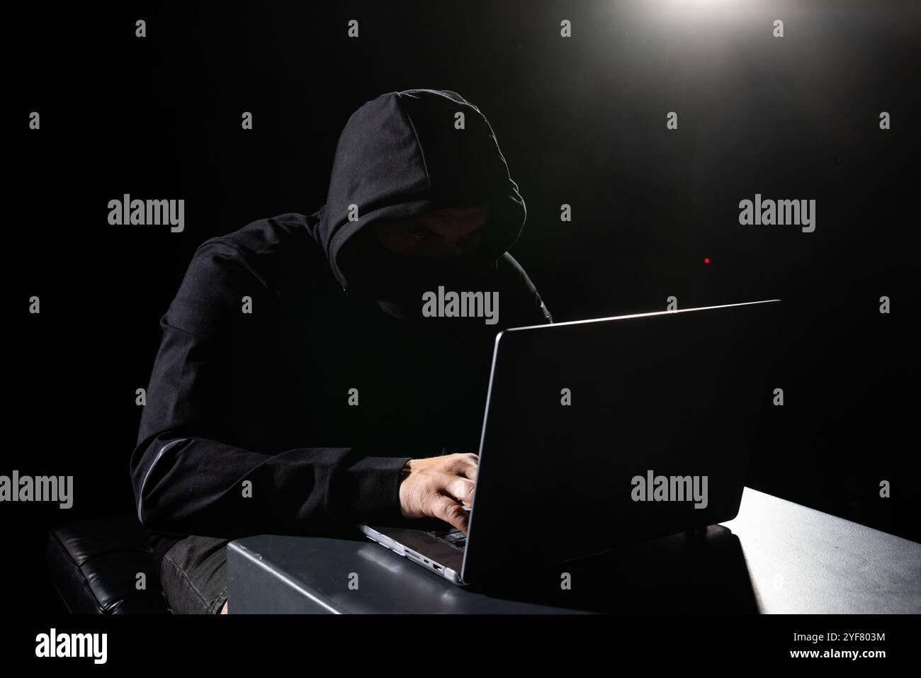 Pirate informatique en Hoodie. Visage sombre masqué. Attaque de pirates informatiques, logiciels infectés par un virus, Web sombre et concept de cybersécurité . Banque D'Images