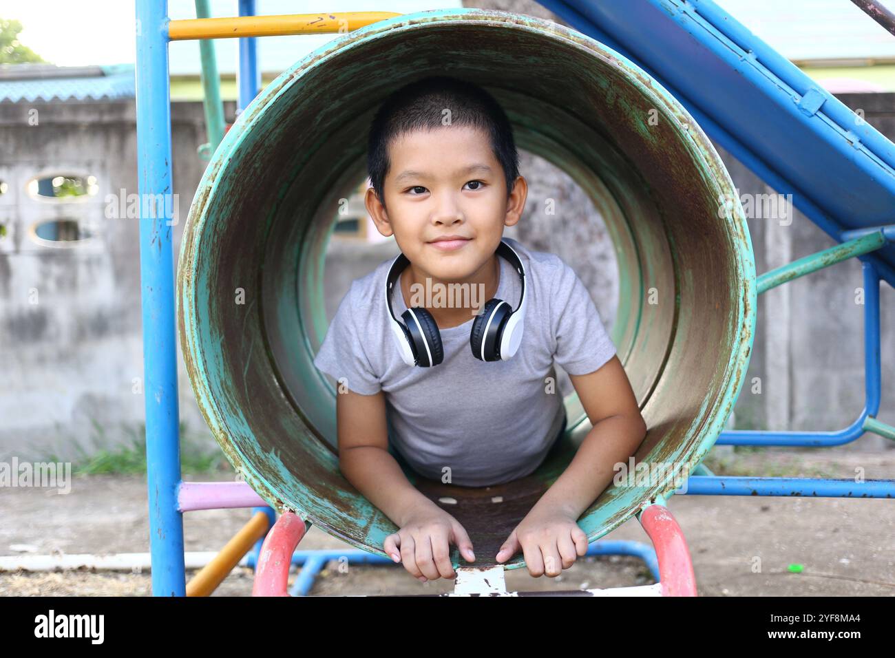 Un enfant heureux aime jouer dans un tube coloré de terrain de jeu, mettant en valeur la joie et l'innocence. Une représentation parfaite des aventures de l'enfance et du plaisir en plein air. Banque D'Images