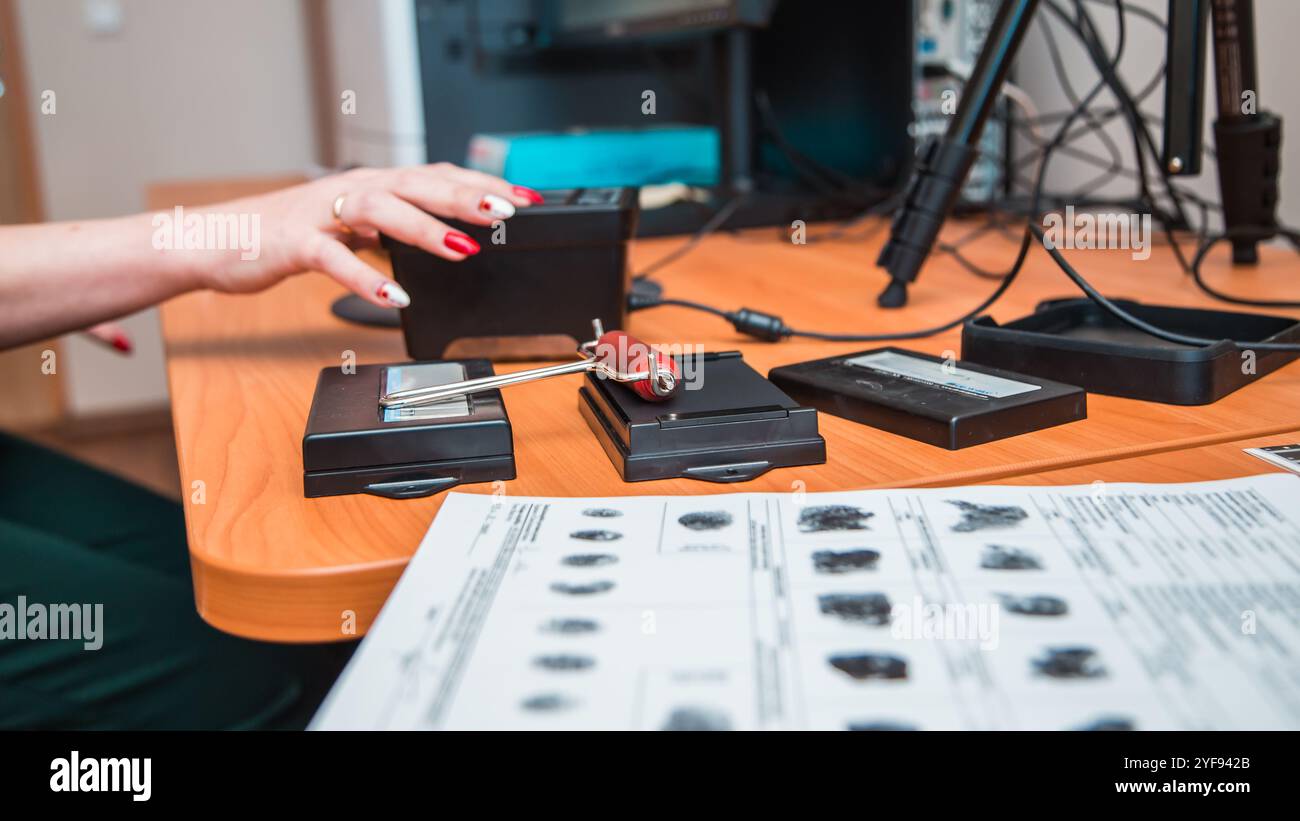 Expert médico-légal prenant des empreintes digitales pour identification avec tampon encreur et rouleau sur le bureau Banque D'Images