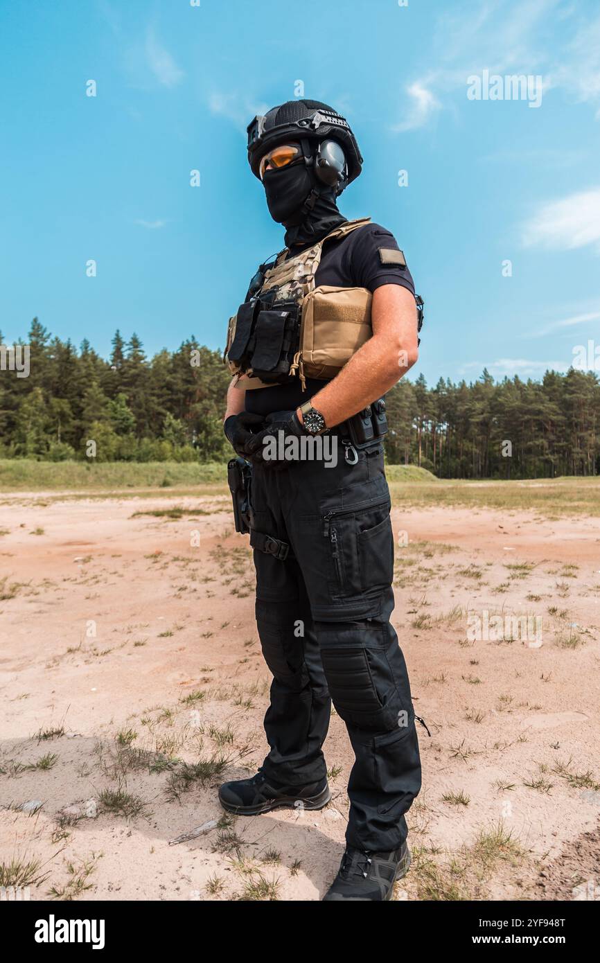 Agents des forces spéciales en équipement tactique pratiquant l'entraînement aux armes à feu dans un champ de tir extérieur sous un ciel nuageux Banque D'Images