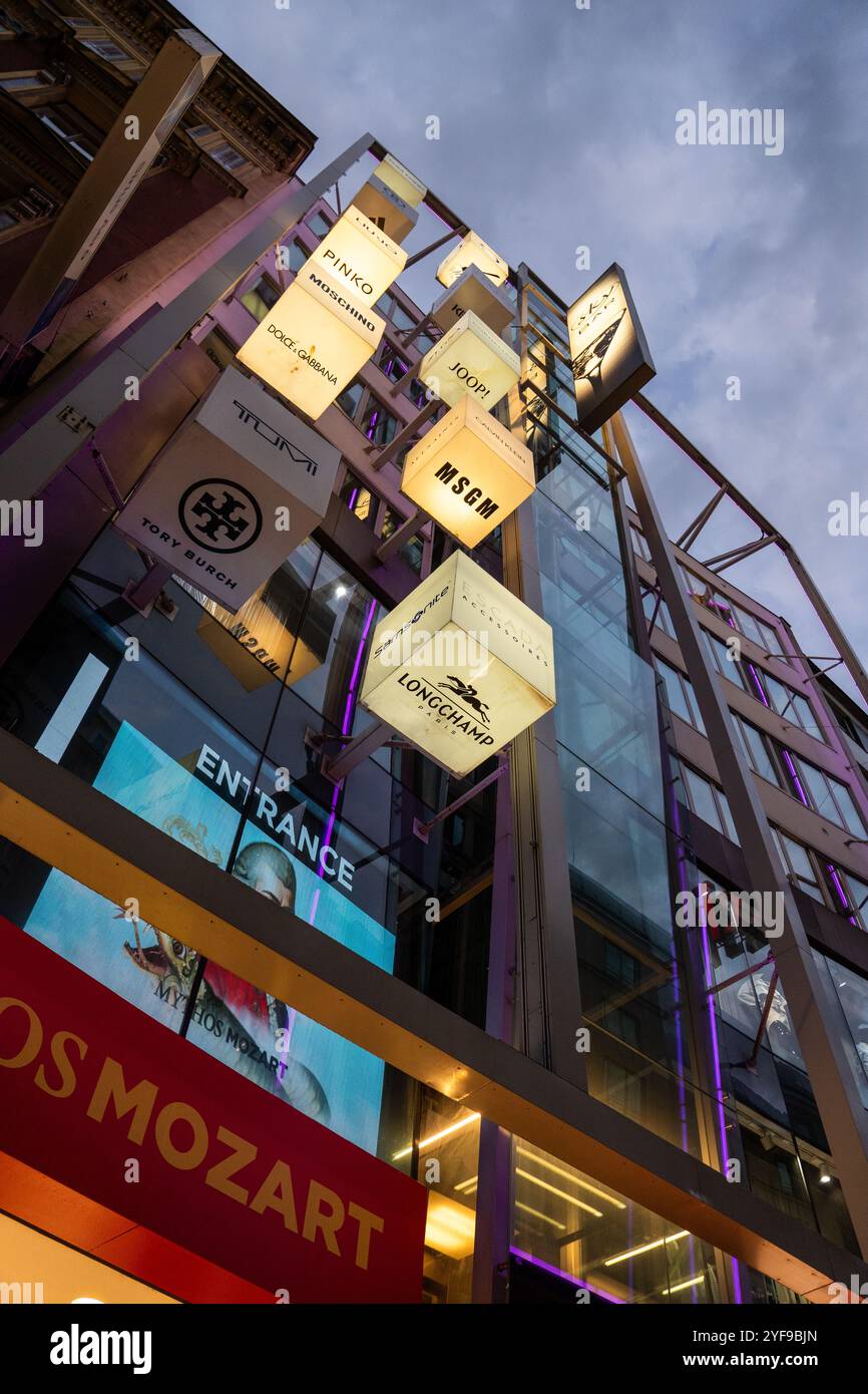 VIENNE, AUTRICHE - 10 AOÛT 2024 : des enseignes de marque de mode de luxe illuminent la rue commerçante Kohlmarkt en soirée. Des marques célèbres comme Moschino, Dolce Banque D'Images