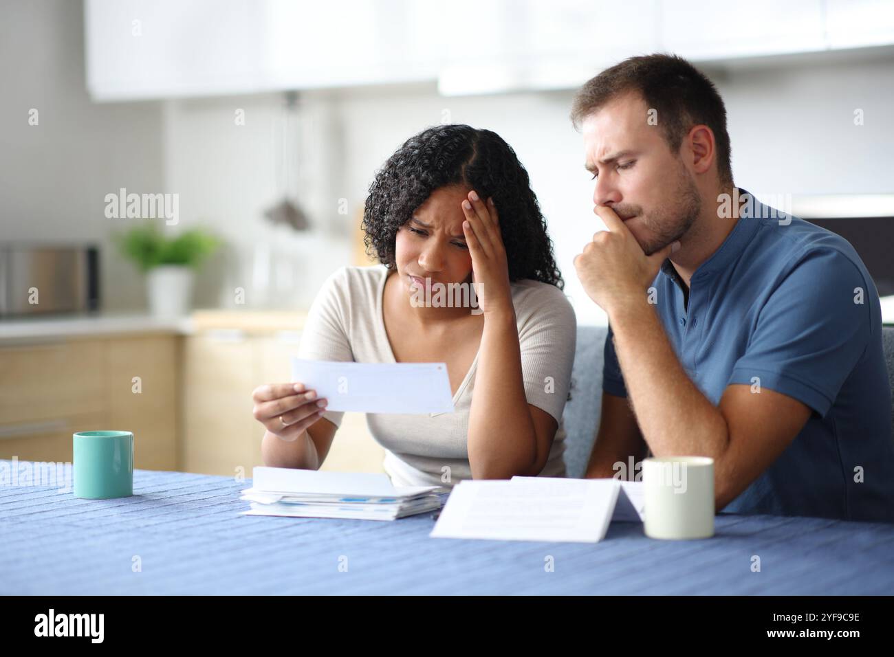 Triste couple ou colocataires vérifiant le relevé bancaire dans la cuisine à la maison Banque D'Images