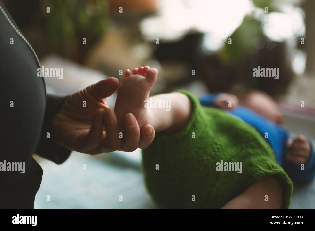 Main de femme âgée tenant les pieds du nouveau-né à la maison Banque D'Images