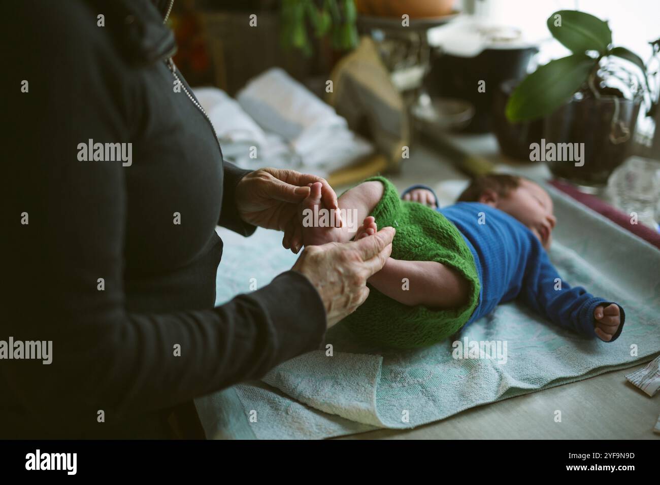 Section médiane d'une femme âgée tenant les pieds d'un nouveau-né à domicile Banque D'Images