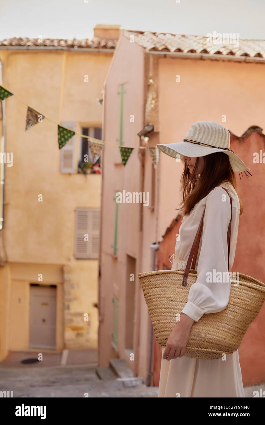 Vue latérale de la belle femme couvrant les yeux avec chapeau de paille Banque D'Images