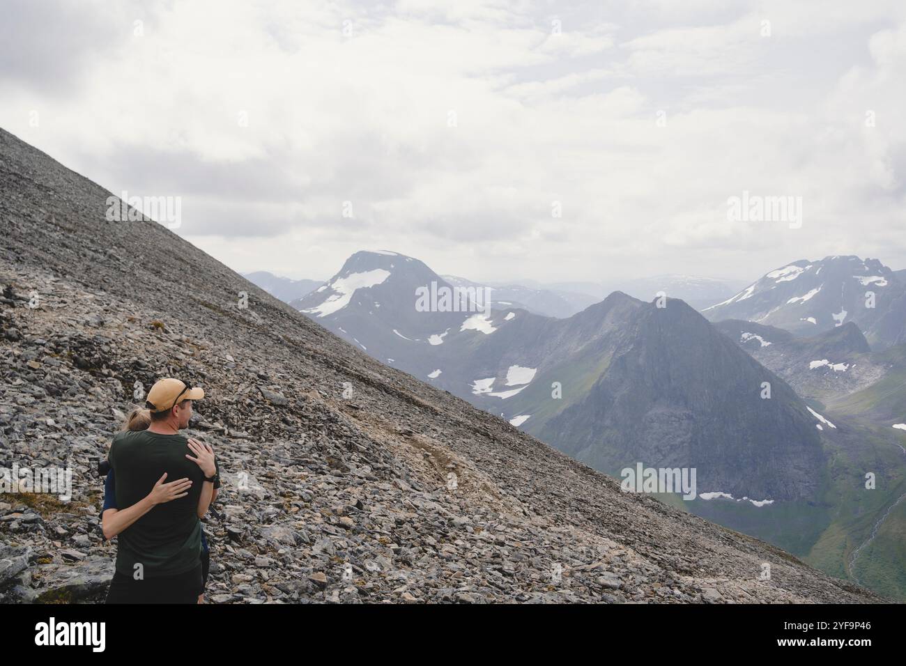 Couple embrassant tout en se tenant sur la montagne contre le ciel nuageux Banque D'Images