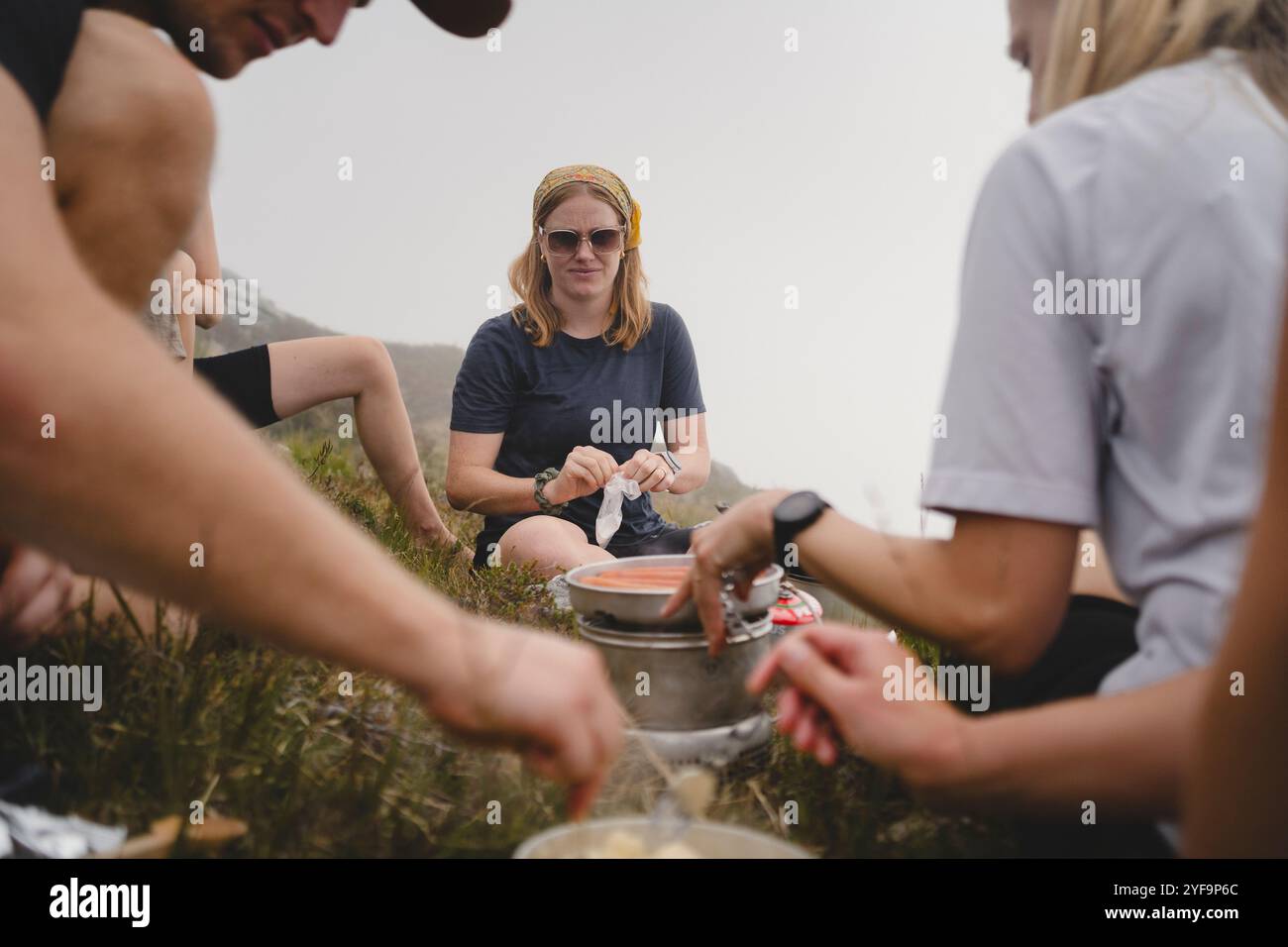 Belle jeune femme appréciant la nourriture avec des amis tout en faisant de la randonnée sur la montagne Banque D'Images