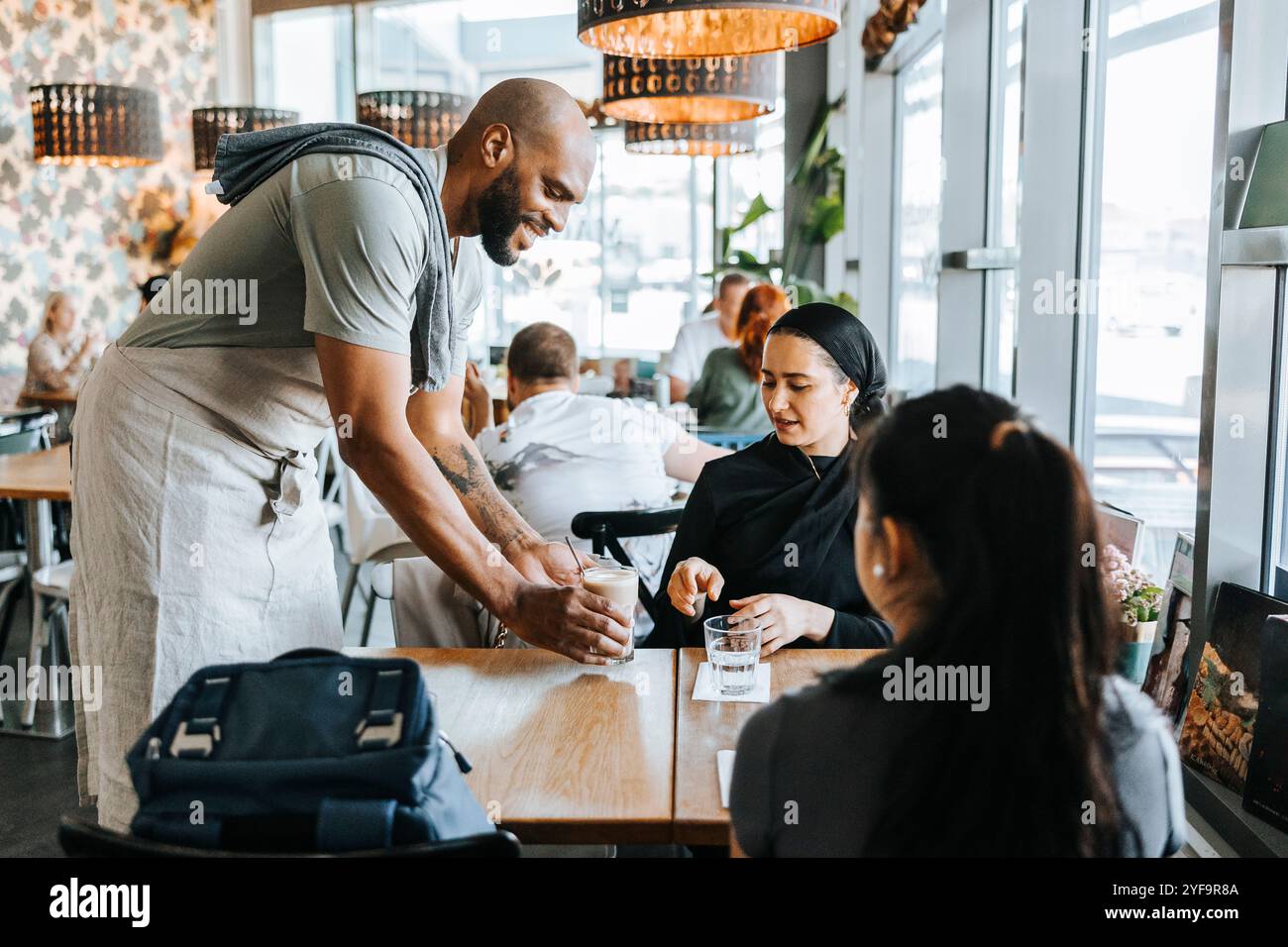 Barista souriant servant du café aux clientes du café Banque D'Images