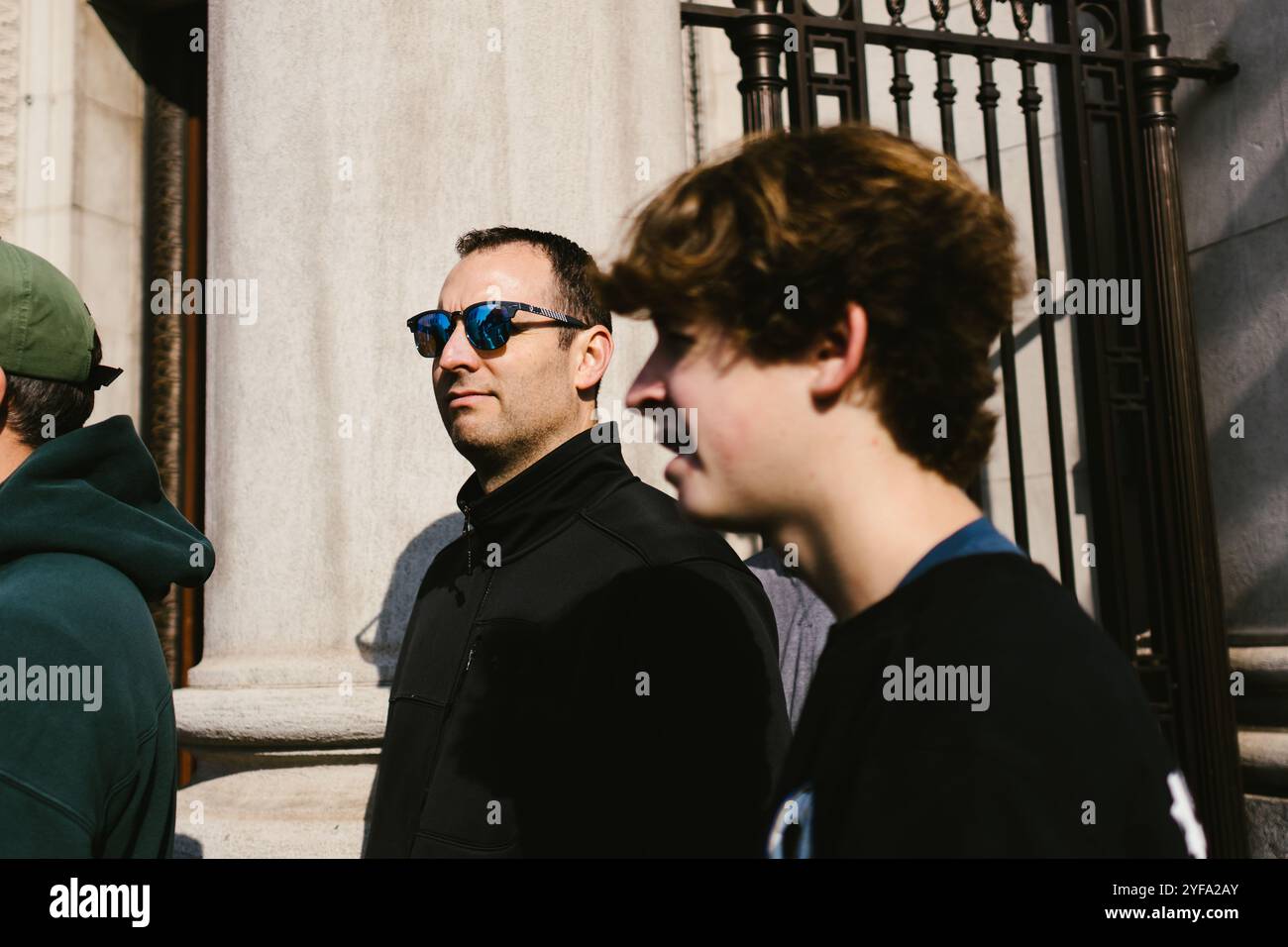 L'homme se tient dans la zone urbaine avec des lunettes de soleil sur près du bâtiment Banque D'Images