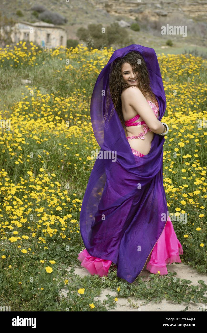 Femme effectuant la danse orientale du ventre portant un costume coloré en extérieur. Dansez dans la rue Banque D'Images