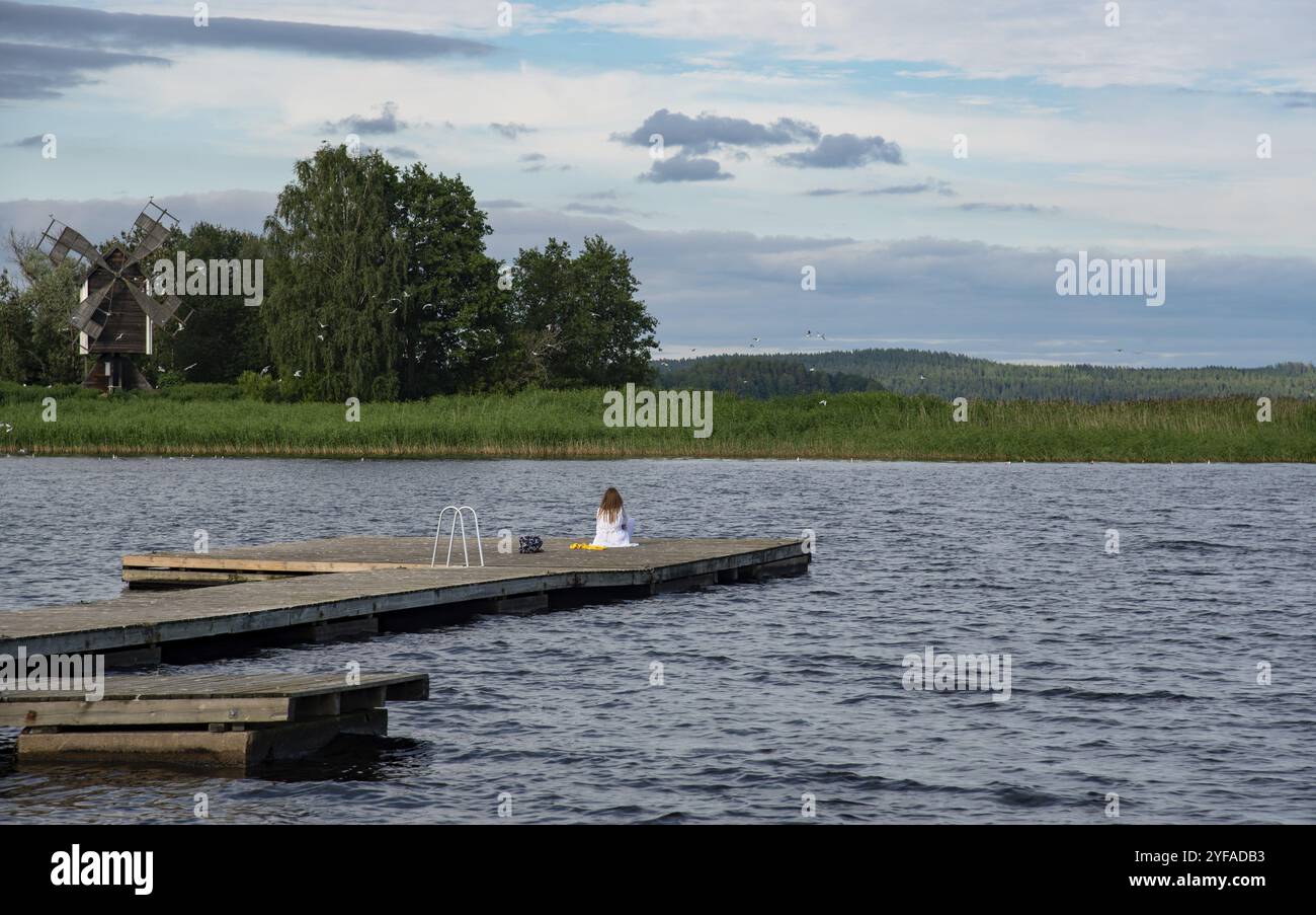 Méditation calme au bord du lac. Jeune femme assise à l'extérieur sur la jetée méditant, Calm Relax Mind. kalallavesi lac kuopio finlande Banque D'Images