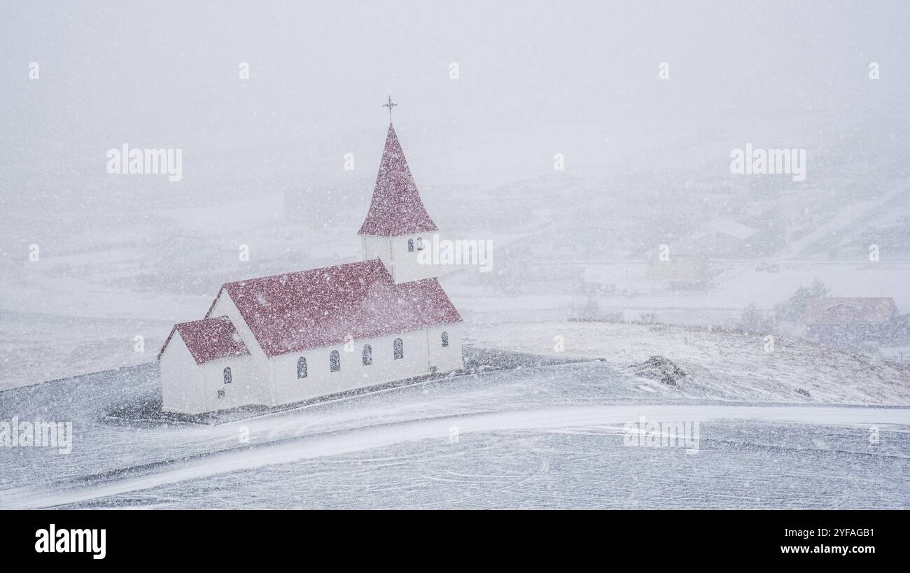 La pittoresque église Vik i Myrdal au sommet de la colline pendant la neige abondante dans le village de vik en Islande en hiver Banque D'Images