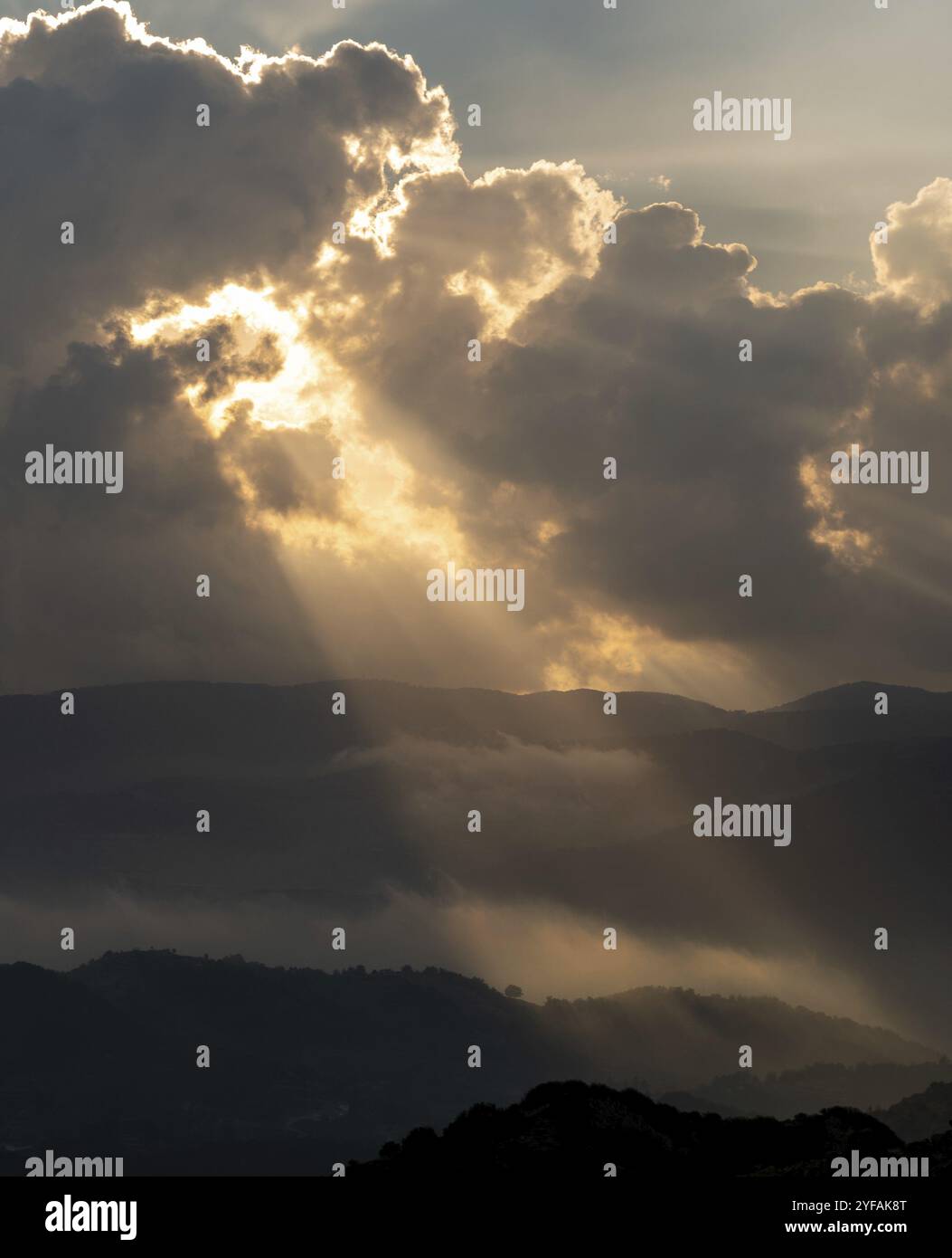 Le soleil brille par des rayons de lumière rayant à travers des nuages sombres sur la montagne au coucher du soleil.Ciel spectaculaire en hiver Banque D'Images