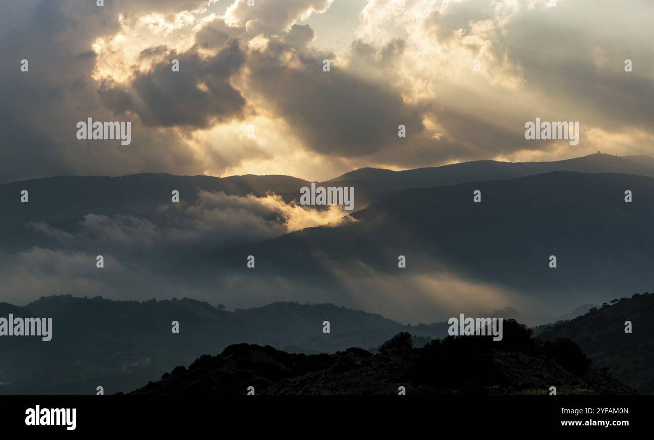 Le soleil brille par des rayons de lumière rayant à travers des nuages sombres sur la montagne au coucher du soleil.Ciel spectaculaire en hiver Banque D'Images