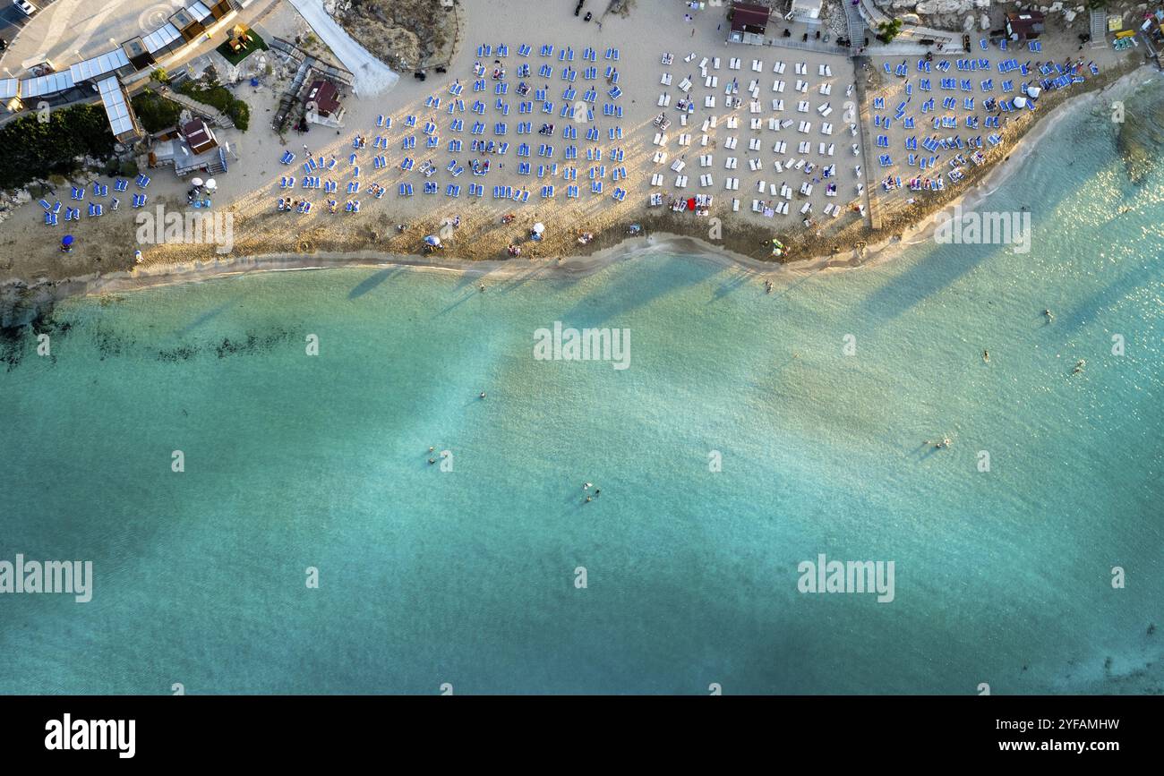 Parasols de plage dans une rangée à la plage de baie de figuiers Protaras Chypre. Vacances d'été station de vacances sable doré Banque D'Images