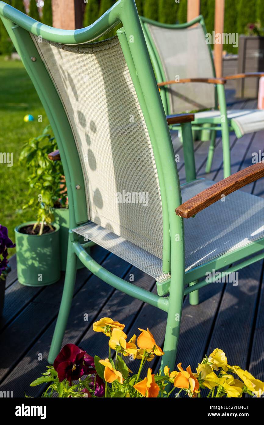 Gros plan de chaises de patio vertes sur une terrasse avec des fleurs colorées au premier plan sur la terrasse Banque D'Images