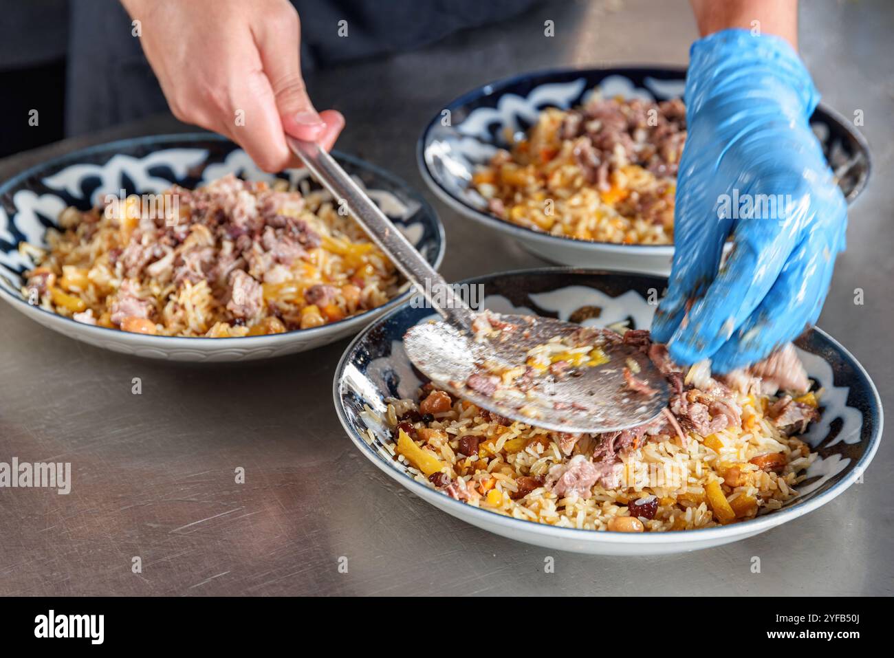 Cuisinière met plov (pilaf) sur des assiettes, Tachkent, Ouzbékistan Banque D'Images