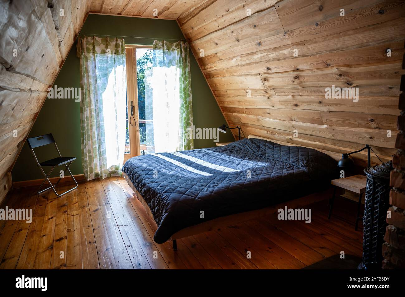 Chambre rustique en bois avec cheminée en briques apparentes et mobilier en bois minimaliste, éclairée par la lumière du soleil. Banque D'Images