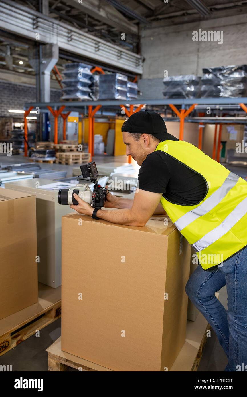 cameraman dans un gilet jaune filme les processus industriels à l'intérieur d'un atelier, en mettant l'accent sur l'attention aux détails et à l'équipement. Banque D'Images