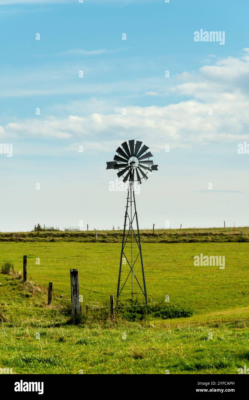 Un moulin à vent se dresse haut dans un champ vert sous un ciel bleu vif. Auvergne. France Banque D'Images