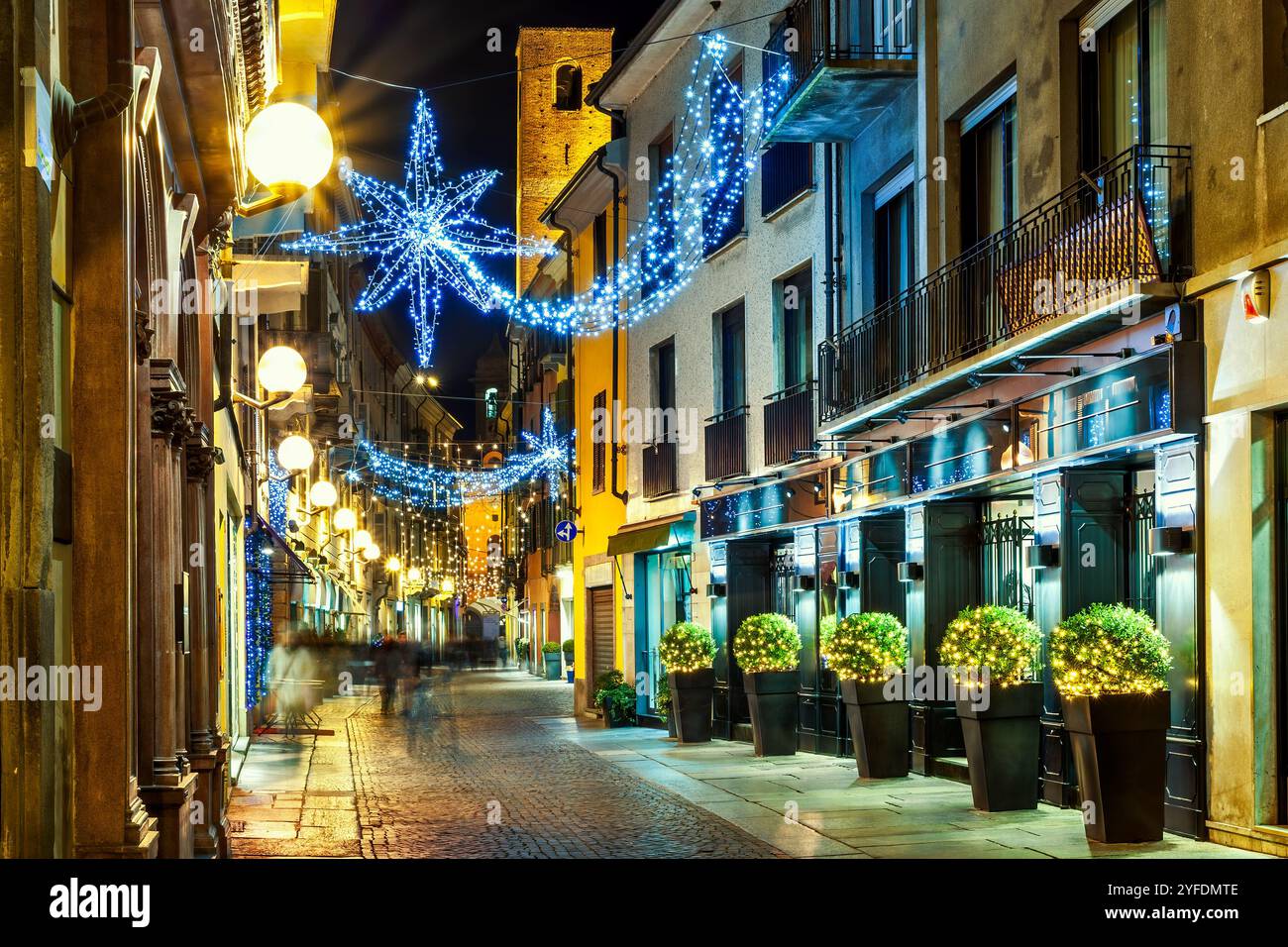 Vue en soirée sur l'étroite rue pavée dans la vieille ville d'Alba illuminée et décorée avec des lumières de Noël. Banque D'Images