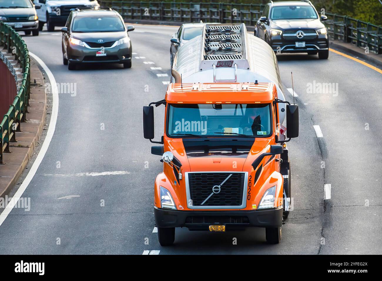 Semi-camion Orange Volvo circulant sur une autoroute courbe à côté d'autres véhicules. Banque D'Images