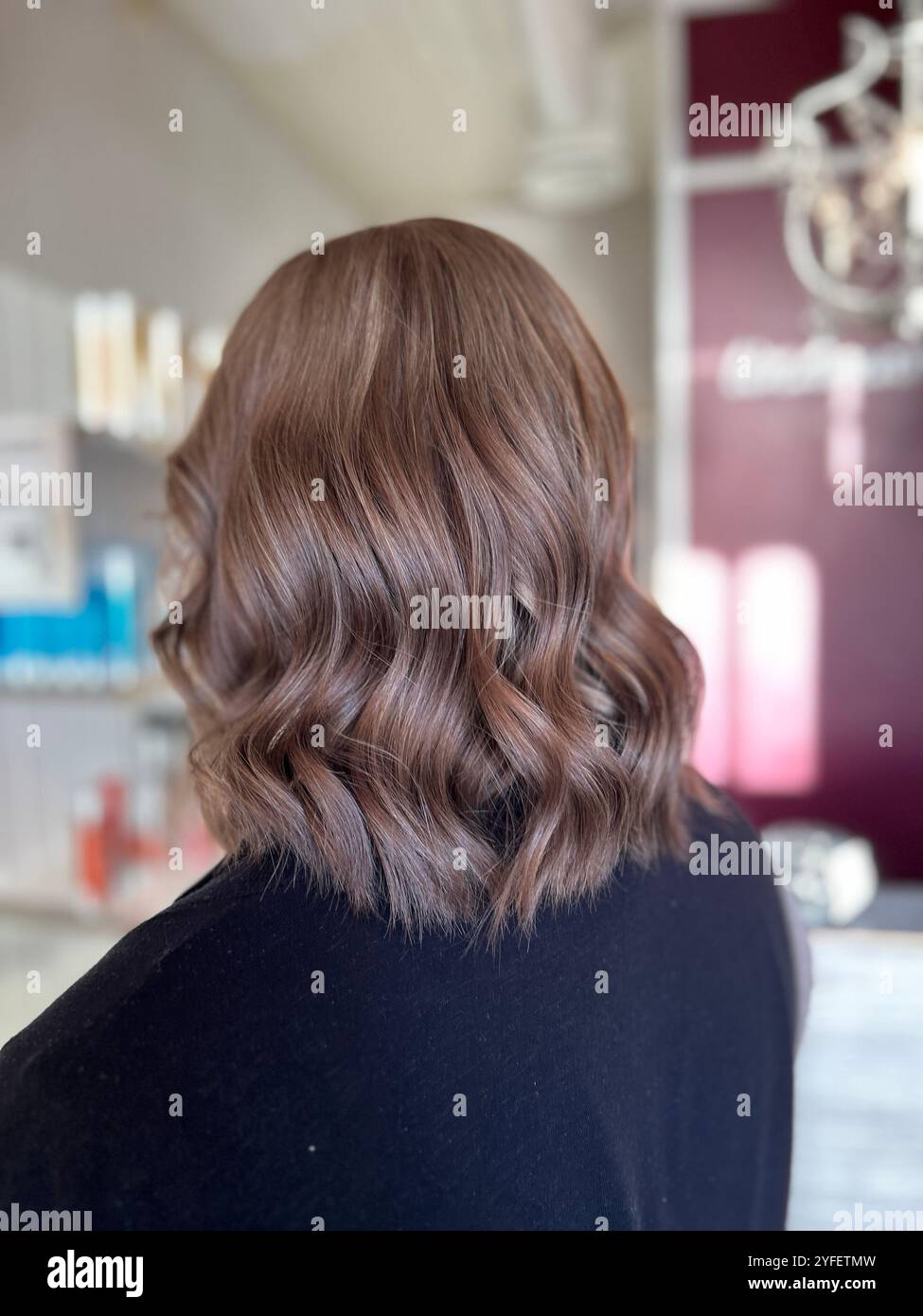 Coiffure aux épaules avec des vagues blond foncé douces et une finition brillante. les reflets subtils et les vagues lisses et texturées ajoutent du mouvement. - Image de stock capturée avec un smartphone