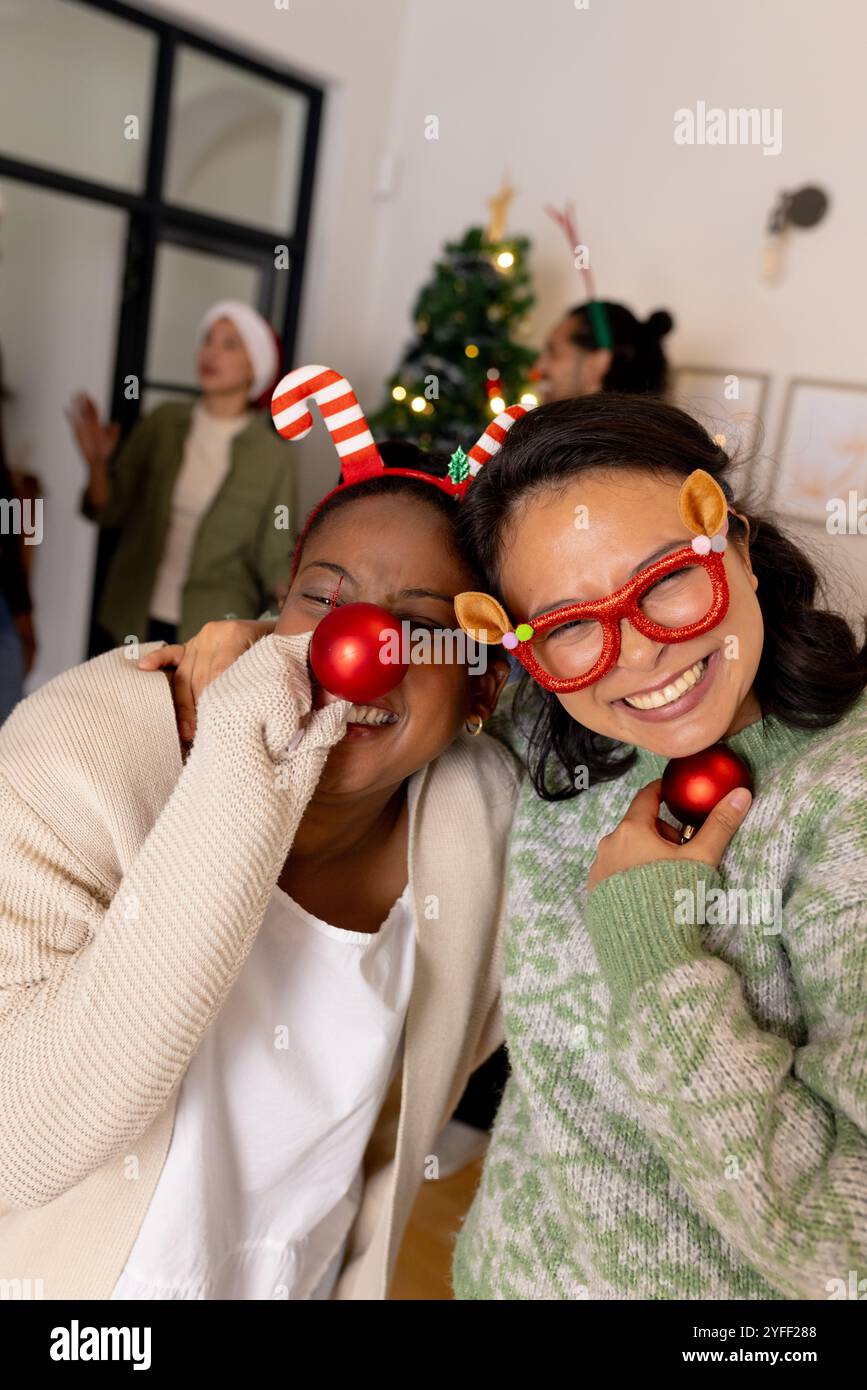 Jeunes amis multiraciaux riant avec des accessoires festifs à la fête de Noël à la maison Banque D'Images