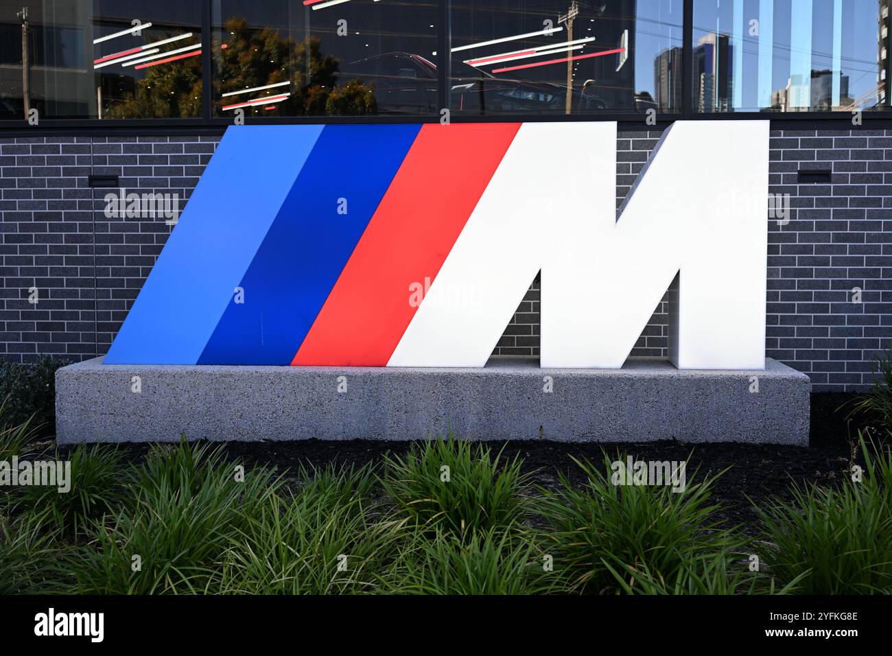 Logo BMW M illuminé, dans un jardin à l'extérieur d'un concessionnaire BMW Banque D'Images