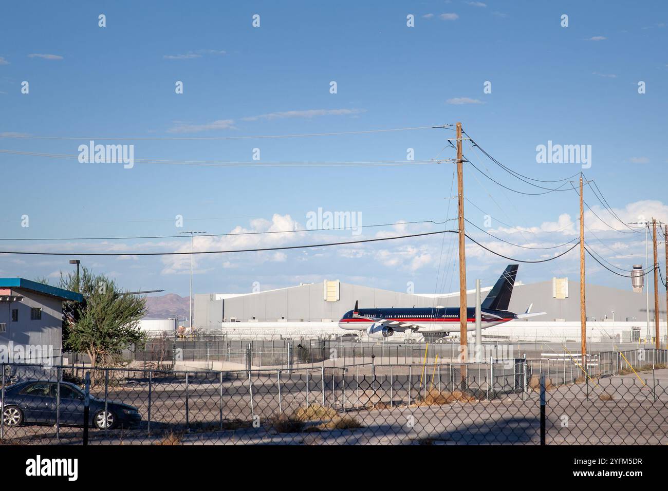 Un avion noir stationné sur le tarmac d'un aéroport américain devant des hangars de maintenance. L'image met en évidence l'exploitation de l'industrie aéronautique Banque D'Images