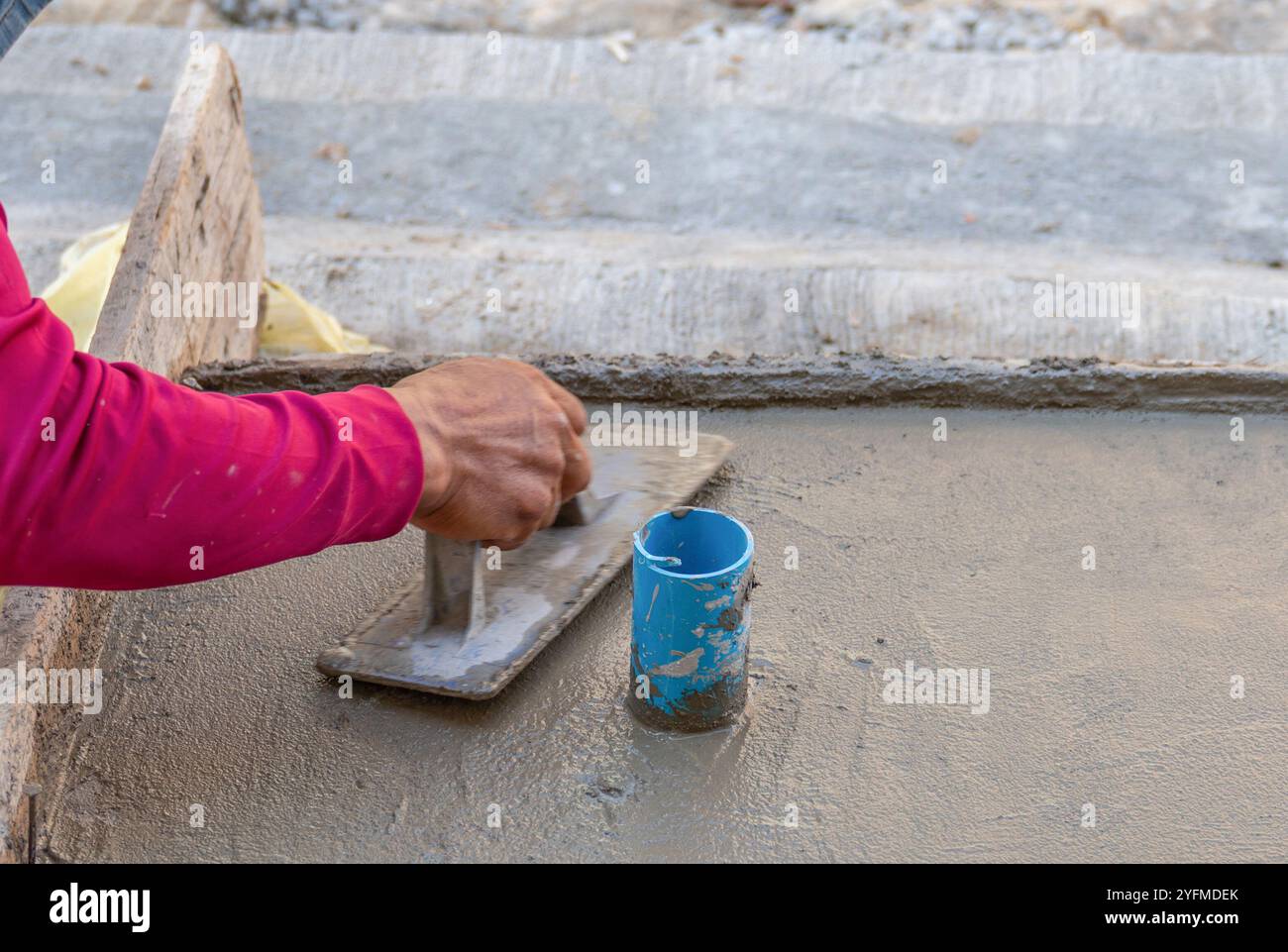 Plâtre homme main utilisant la truelle pour plâtrer le ciment sur le sol en béton. Banque D'Images