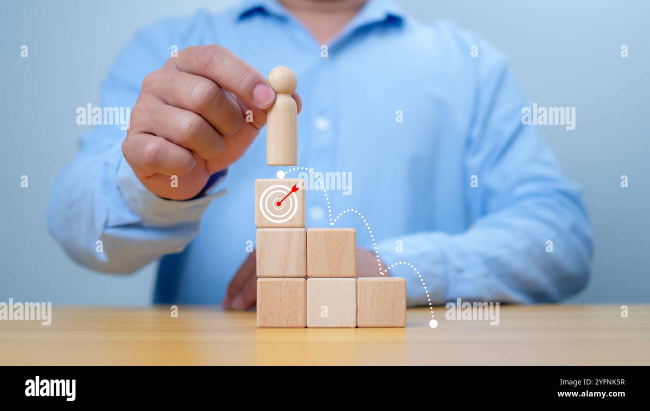 Hand Man place le dessus en bois de l'état ou le gagnant, concept de succès, de victoire et d'accomplissement dans les affaires. Un homme tenant un modèle de poupée en bois debout Banque D'Images