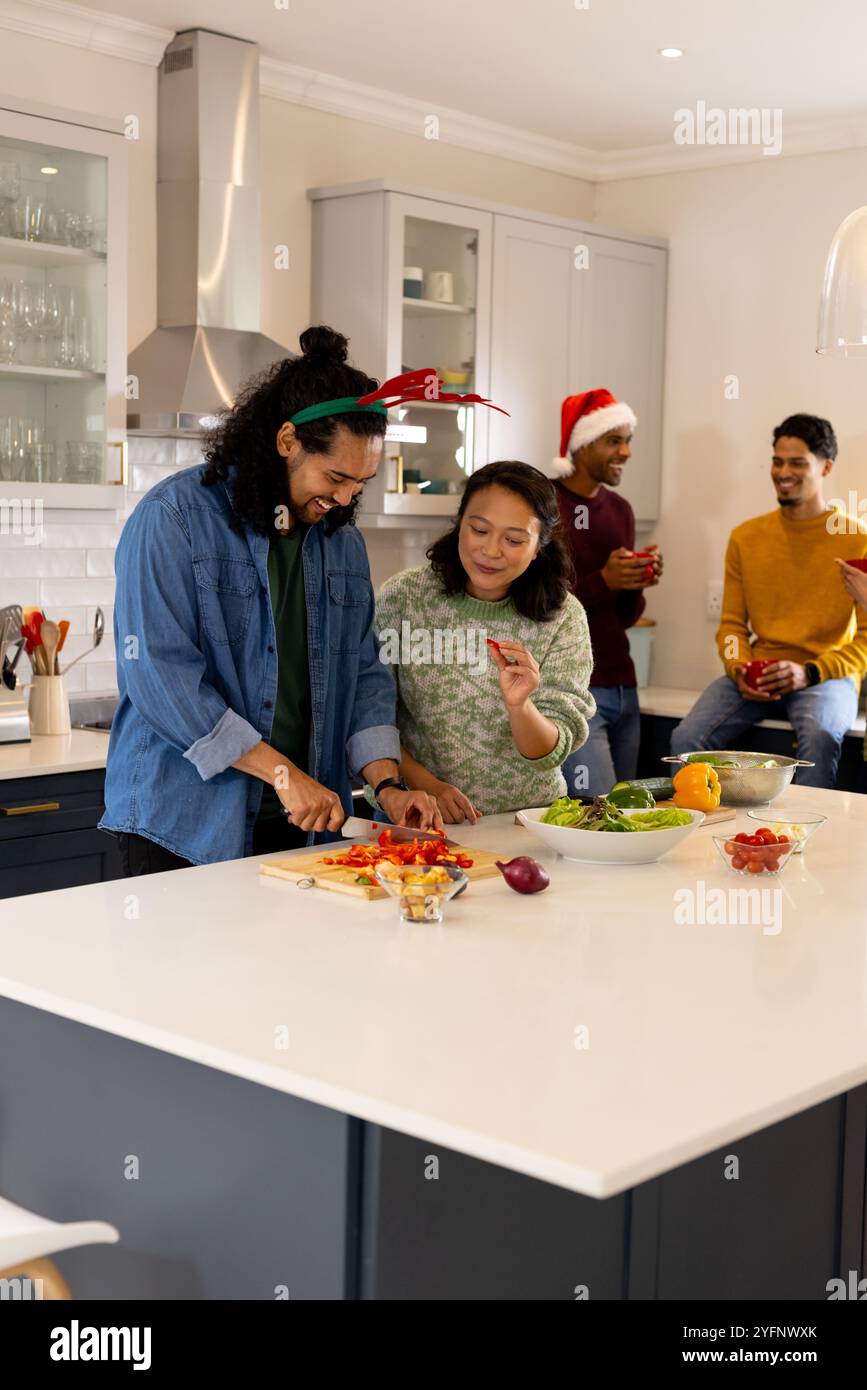 Temps de Noël, amis multiraciaux préparant le repas de vacances ensemble dans la cuisine, à la maison Banque D'Images