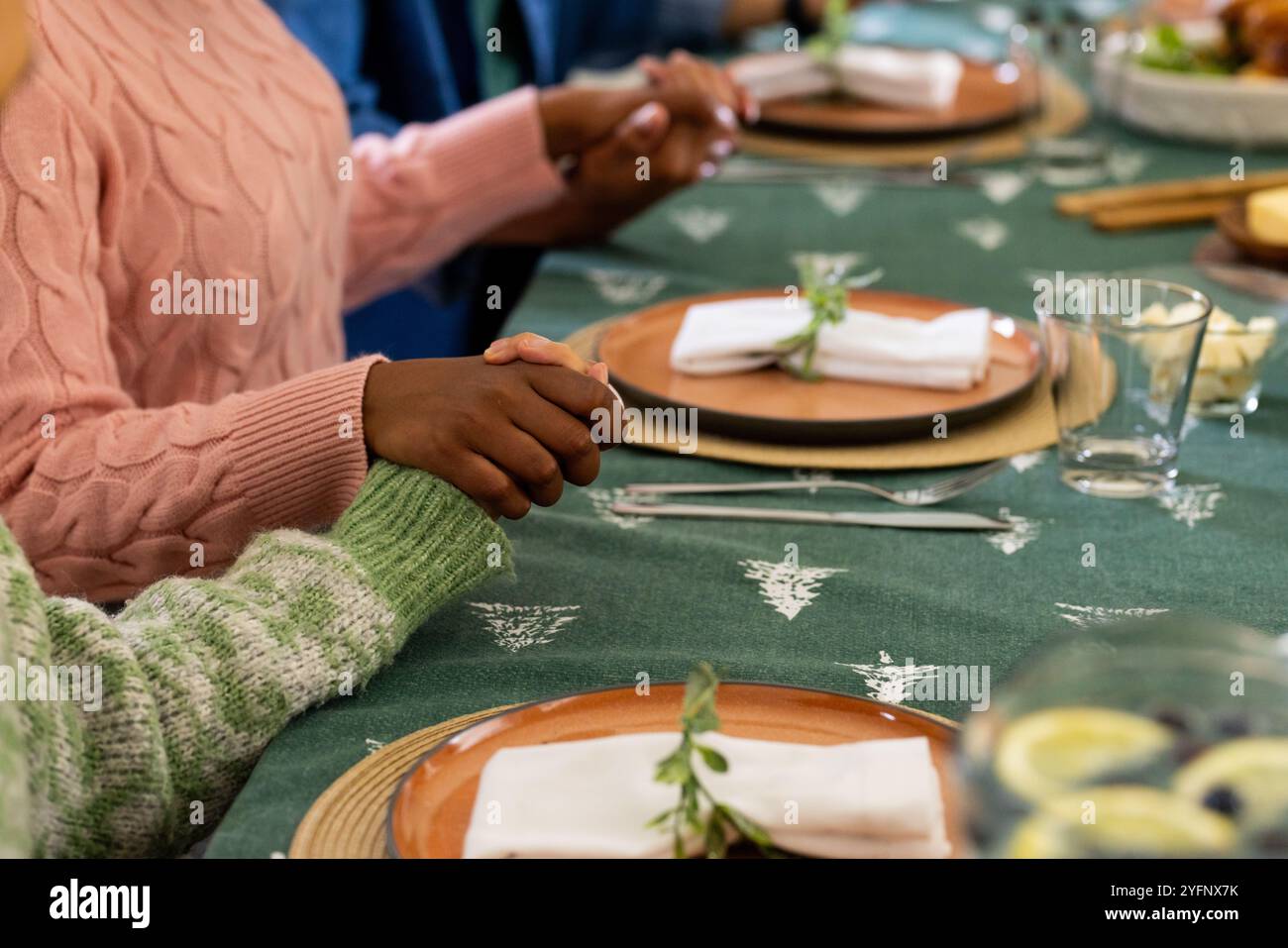 Temps de Noël, amis multiraciaux se tenant la main à la table festive, à la maison Banque D'Images
