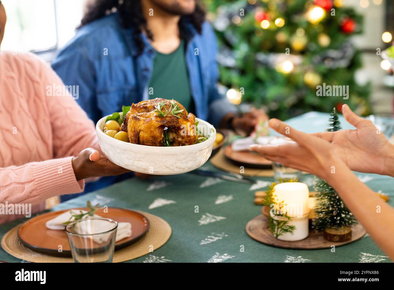 Amis multiraciaux partageant un repas de fête à la table de Noël avec des décorations de vacances, à la maison Banque D'Images