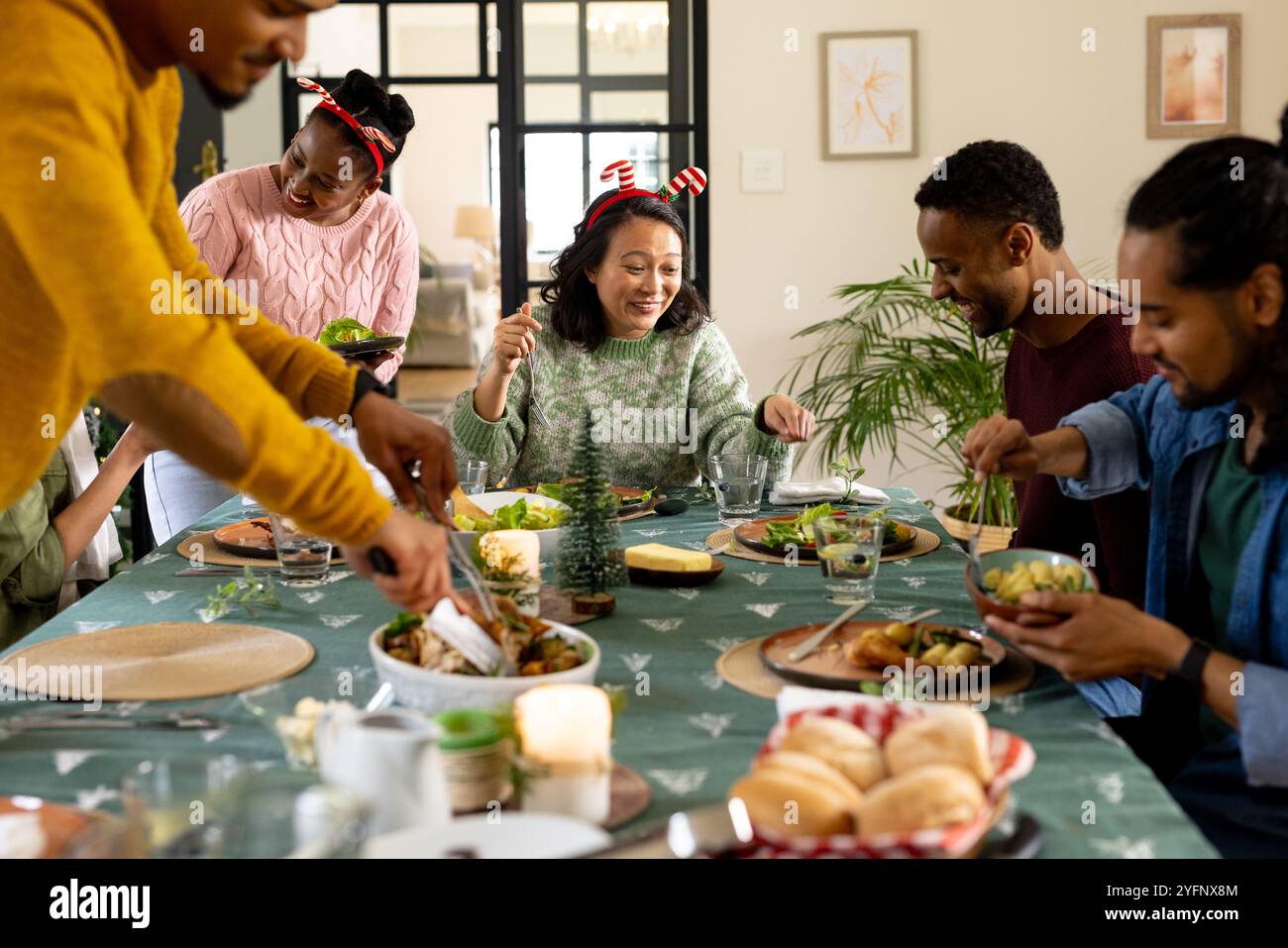 Temps de Noël, amis multiraciaux profitant d'un repas de vacances festif ensemble à la maison Banque D'Images