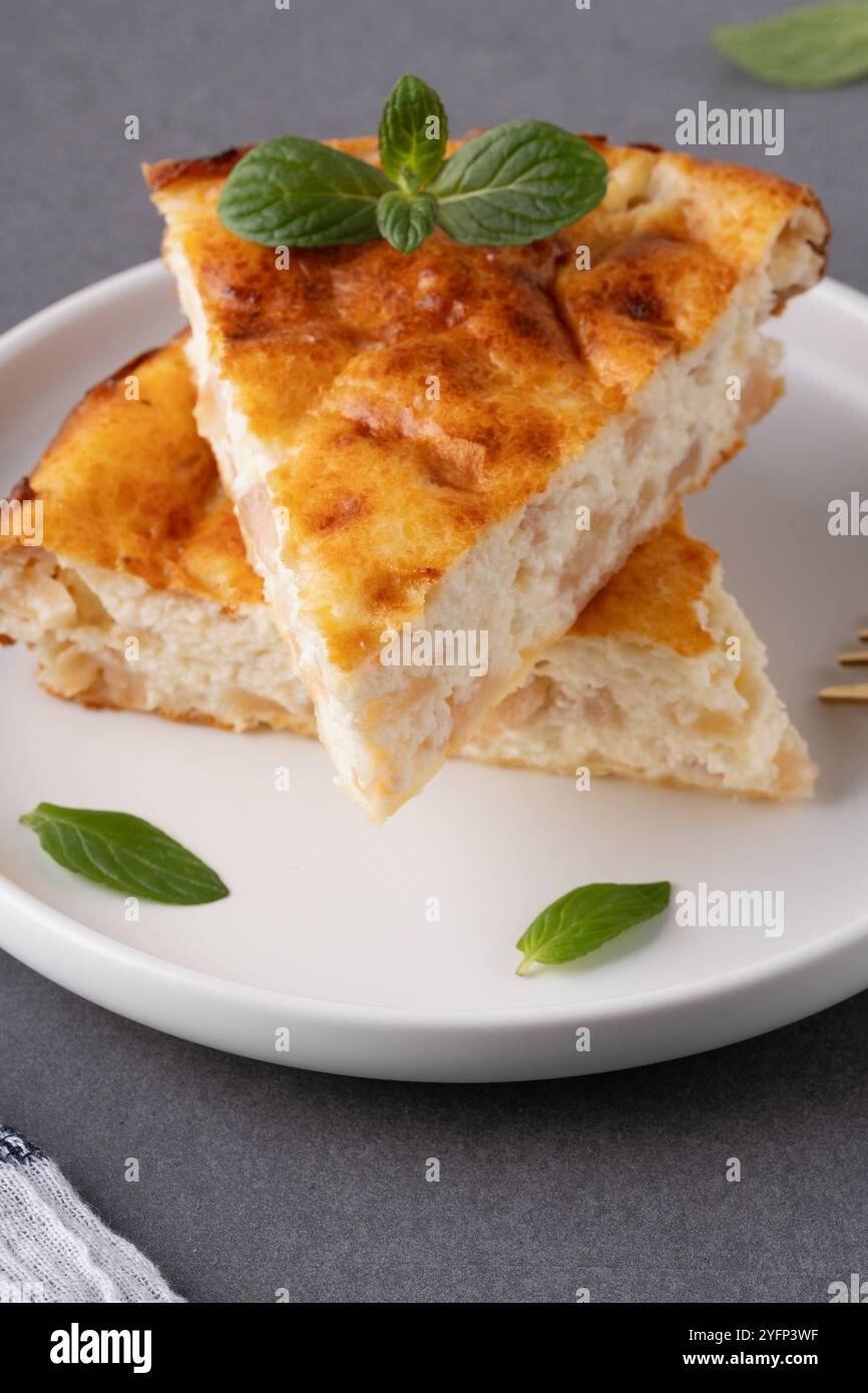Délicieuse tarte aux pommes maison servie avec du café et garnie de feuilles de menthe sur une table de cuisine confortable Banque D'Images