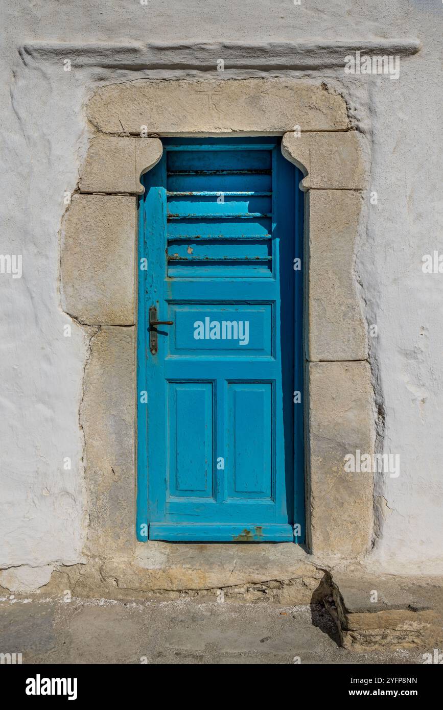 Vieille porte bleue texturée dans un mur blanc en Grèce Banque D'Images
