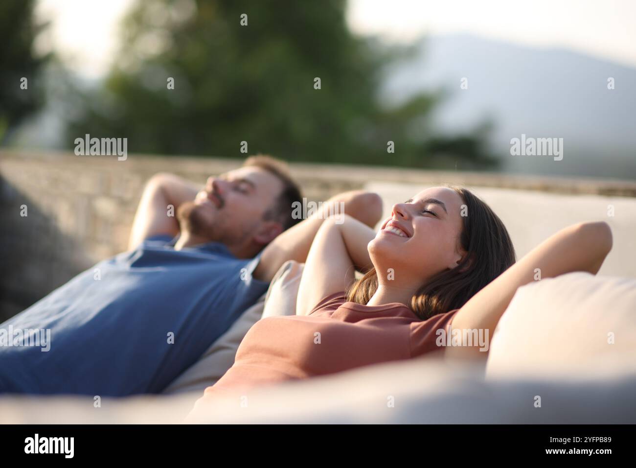 Couple heureux se relaxant assis dans un canapé-terrasse Banque D'Images