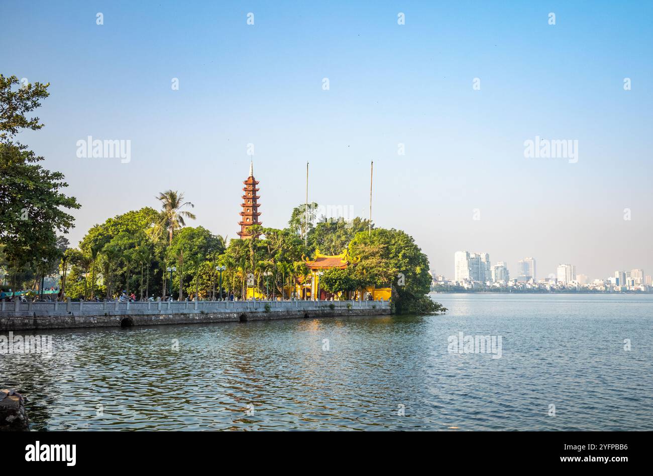 L'ancienne pagode Tran Quoc sur le lac de l'Ouest avec des bâtiments modernes de grande hauteur au loin à Hanoi, Vietnam. La pagode remonte au 6ème cent Banque D'Images
