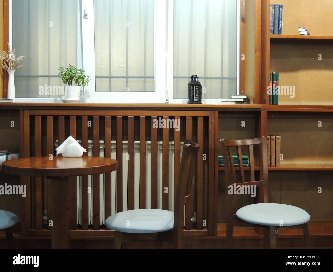 chaises et table près de la fenêtre à l'intérieur d'un café ou d'une pièce avec des livres sur les étagères, un lieu public pour étudier ou lire sans personne Banque D'Images