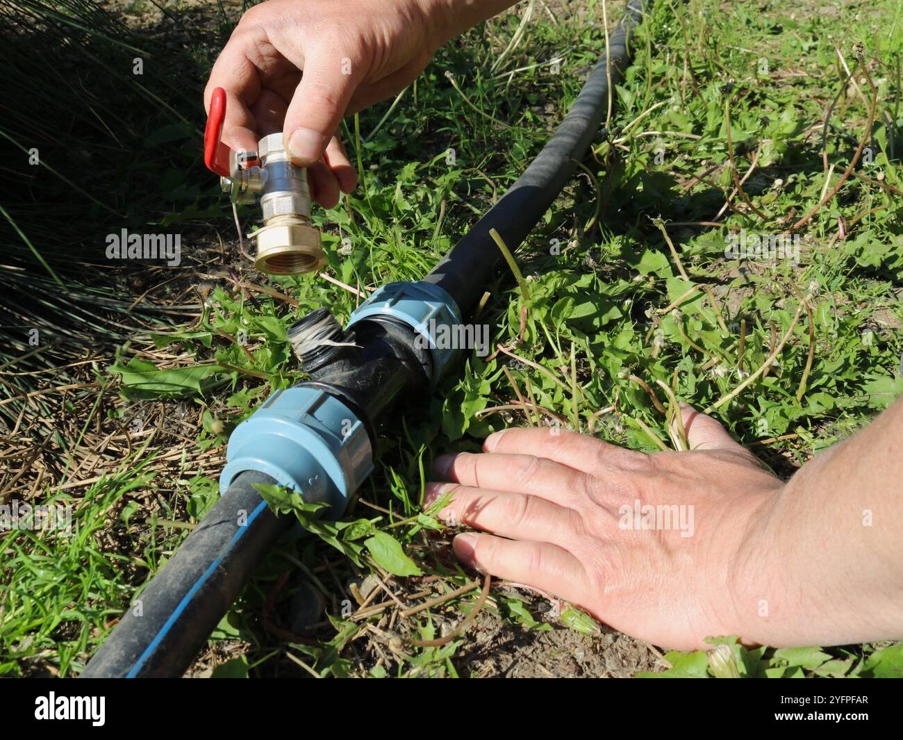 montage d'une vanne sur un raccord dans un système d'irrigation de jardin, installation de parties d'une canalisation de jardin pour irriguer le sol ou la pelouse, une poignée Banque D'Images